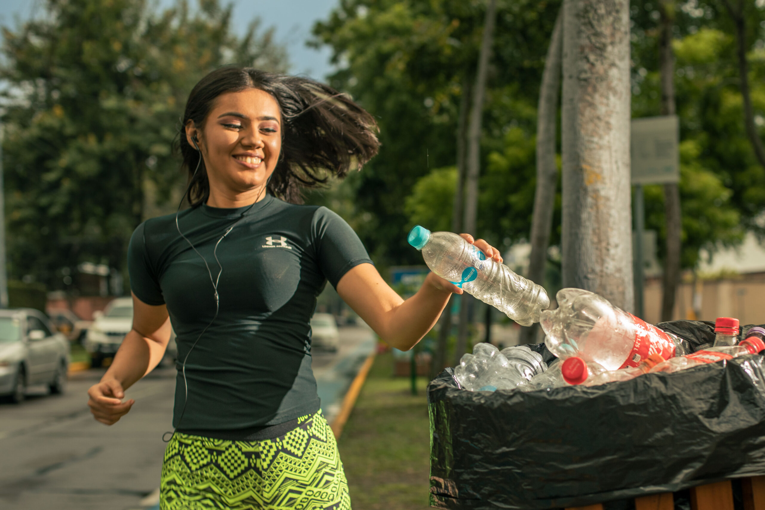 Chica depositando una botella plástica en un contenedor